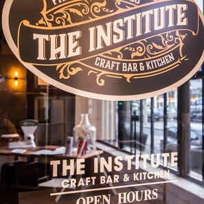 Schild für "The Institute Craft Bar & Kitchen" mit dekorativem Design und Schriftzug, der es als Craft Bar und Küche kennzeichnet.