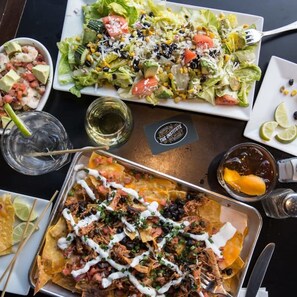 Et spisebord med forskellige retter, herunder nachos, en salat og en rejedish.