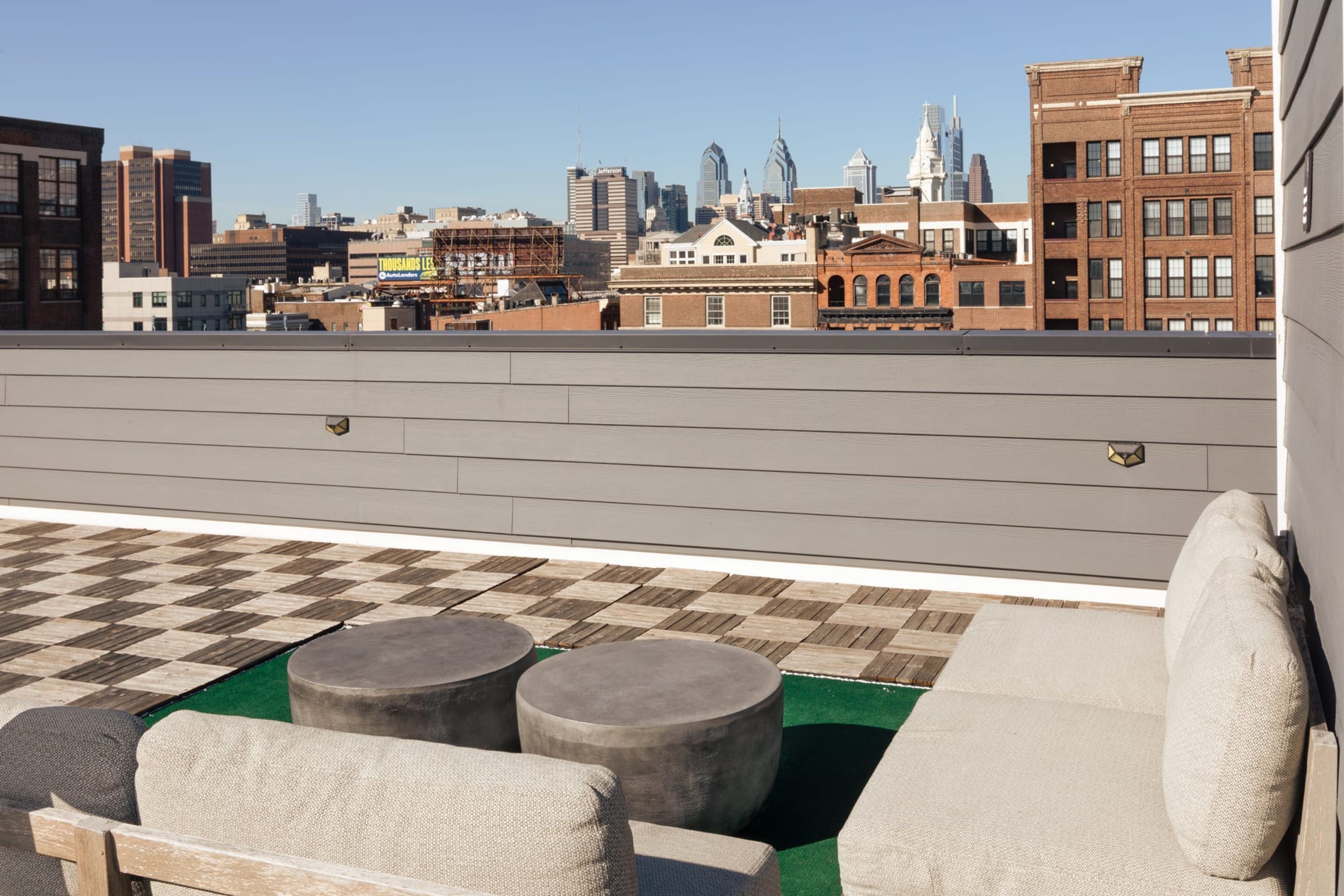 A rooftop terrace with a checkered floor, a sofa, and two round tables.