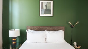 A neatly made bed with white linens, a glass side table with a lamp, and a framed picture on the wall. - Sosuite Corner 1BR Apt w W/d, Shared Roofdeck (Philadelphia)