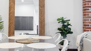 A dining area with a wooden herringbone-patterned wall, a large mirror, and a table with white chairs and woven placemats. - Sosuite 2BR Penthouse w W D Gym On-site Bar (Philadelphia)