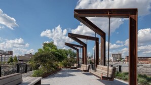 An outdoor seating area with benches and a metal structure, overlooking a cityscape. - Sosuite 2BR Penthouse w W D Gym On-site Bar (Philadelphia)