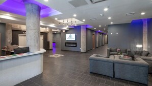 A modern lobby with a reception desk, seating area, and a large pillar. - Sosuite 2BR Penthouse w W D Gym On-site Bar (Philadelphia)