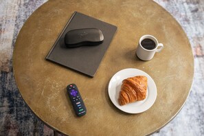 A round table with a remote control, a book, a cup of coffee, and a croissant. - Sosuite 1BR Apt w W/d, Shared Roofdeck (Philadelphia)