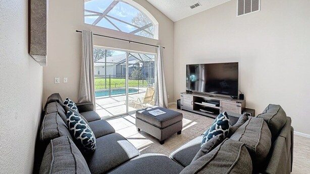 A modern living room with a large TV, comfortable seating, and a sliding glass door leading to a patio.