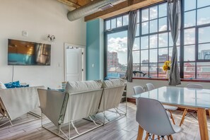 Ein moderner Konferenzraum mit großem Tisch, weißen Stühlen und gepolsterten Sitzgelegenheiten.
