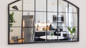 Een moderne keuken met witte kastjes, roestvrijstalen apparatuur en een ronde eettafel met stoelen.