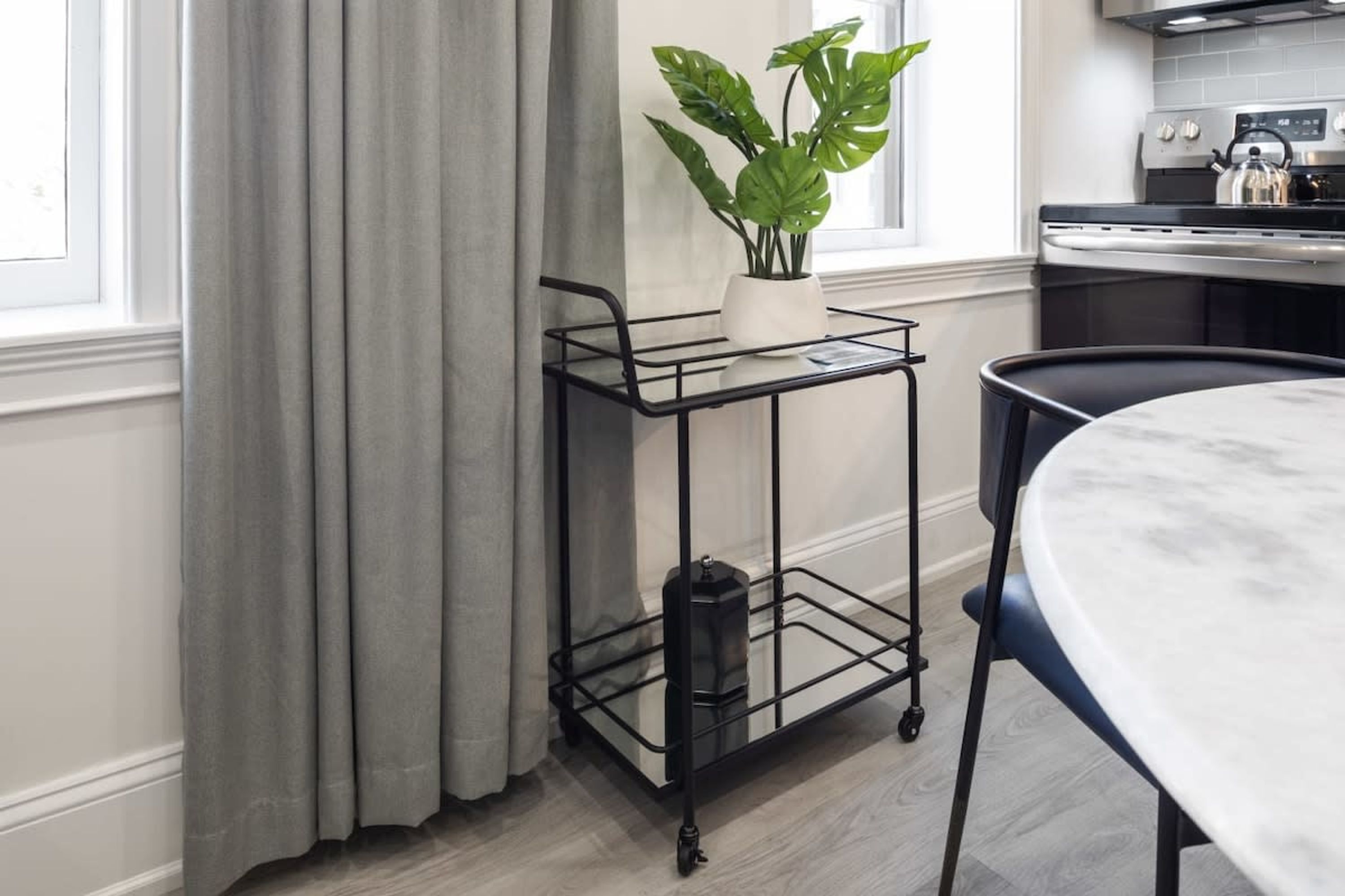 Een keuken met een metalen karretje, een potplant en een marmeren tafel.
