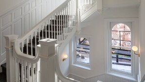 Een witte trap met sierleuningen en een uitzicht op een bakstenen gebouw.