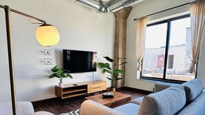 A modern living room with a sofa, a coffee table, a TV, and a large window.