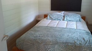 A bedroom with a wooden bed, white walls, a blackboard, and a hanging light fixture. - Urlaub in der Meise (Winsen (Aller))