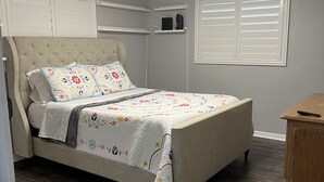 A bedroom with a bed, a wooden nightstand, a wardrobe, and a ceiling light fixture.