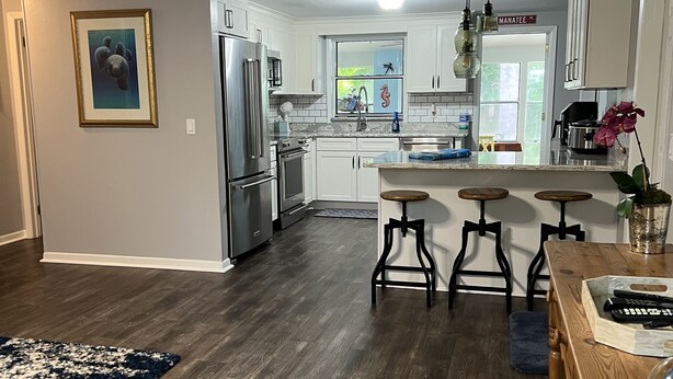 A modern kitchen with stainless steel appliances, a dining area with bar stools, and a large window with decorative elements.