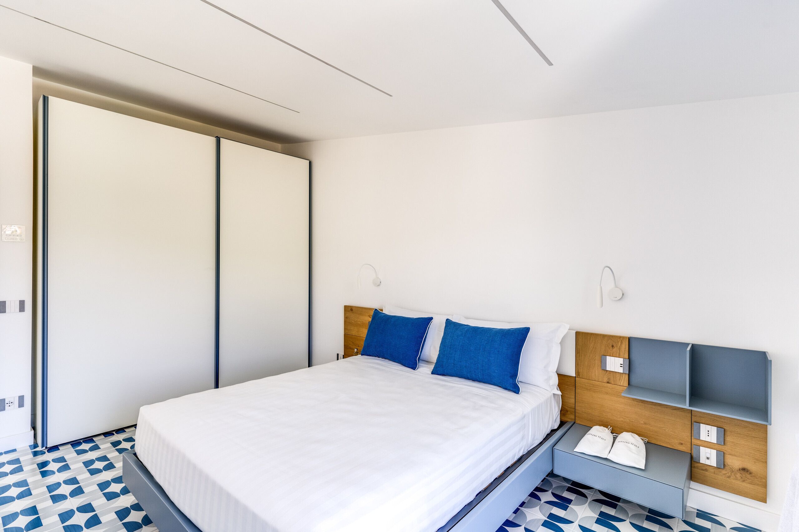Een moderne slaapkamer met een bed, een kledingkast en een nachtkastje met een lamp.