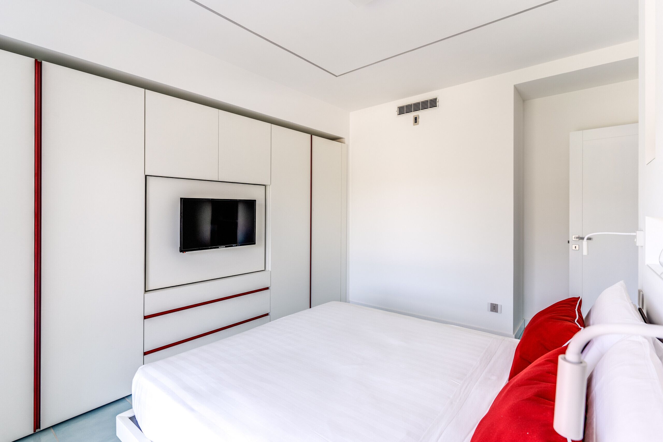 Et moderne hotelværelse med en seng, et fjernsyn ophængt på væggen og en dør med teksten "ROOM 1".