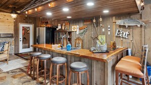 Una cocina rústica con paredes de madera, una barra con taburetes y un refrigerador.