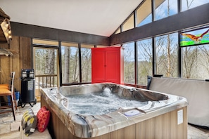 Un bain à remous dans une pièce dotée de grandes fenêtres, d’un meuble rouge et d’un poisson décoratif accroché au mur.