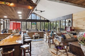 Un vaste espace de vie comprenant une grande table à manger en bois, des sièges confortables et une vue dégagée grâce à de grandes fenêtres.