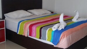 Una cama con una colcha a rayas y dos toallas blancas.