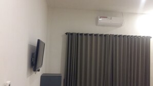 Una habitación con televisor de pared, un radiador y una ventana con cortinas.