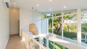 Ein modernes Interieur mit Balkon, großen Fenstern und einer hängenden Leuchte.