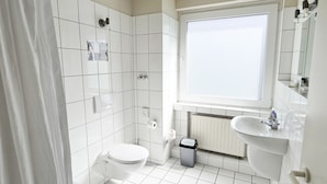 A modern bathroom with a toilet, sink, and bathtub. - guestified. LIYANA Hotel (Ratingen)