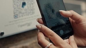 A person holding a smartphone displaying a QR code for PayPal payment. - guestified. LIYANA Hotel (Ratingen)