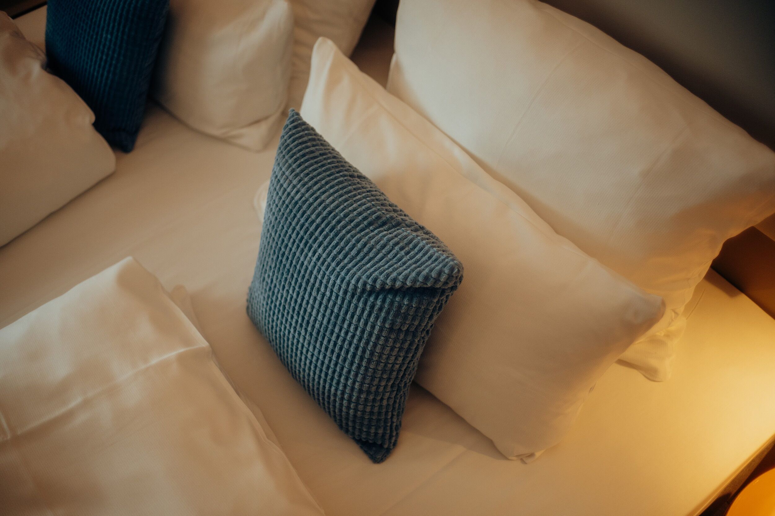 A bed with white and blue pillows.