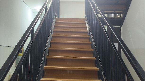 Un escalier en bois avec des rampes noires menant à l’étage supérieur.