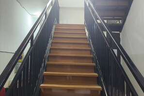 Eine Holztreppe mit schwarzen Geländern, die zu einer oberen Etage führt.
