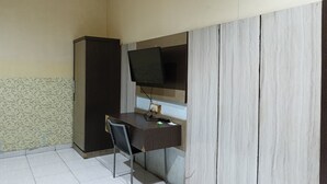 Une petite pièce comprenant un bureau, une chaise, un téléviseur fixé au mur et une armoire.