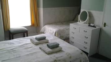 Un dormitorio con dos camas, un aparador con espejo y una ventana con cortinas.