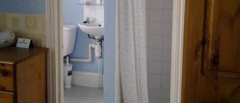 Un baño con inodoro, lavamanos y zona de ducha.
