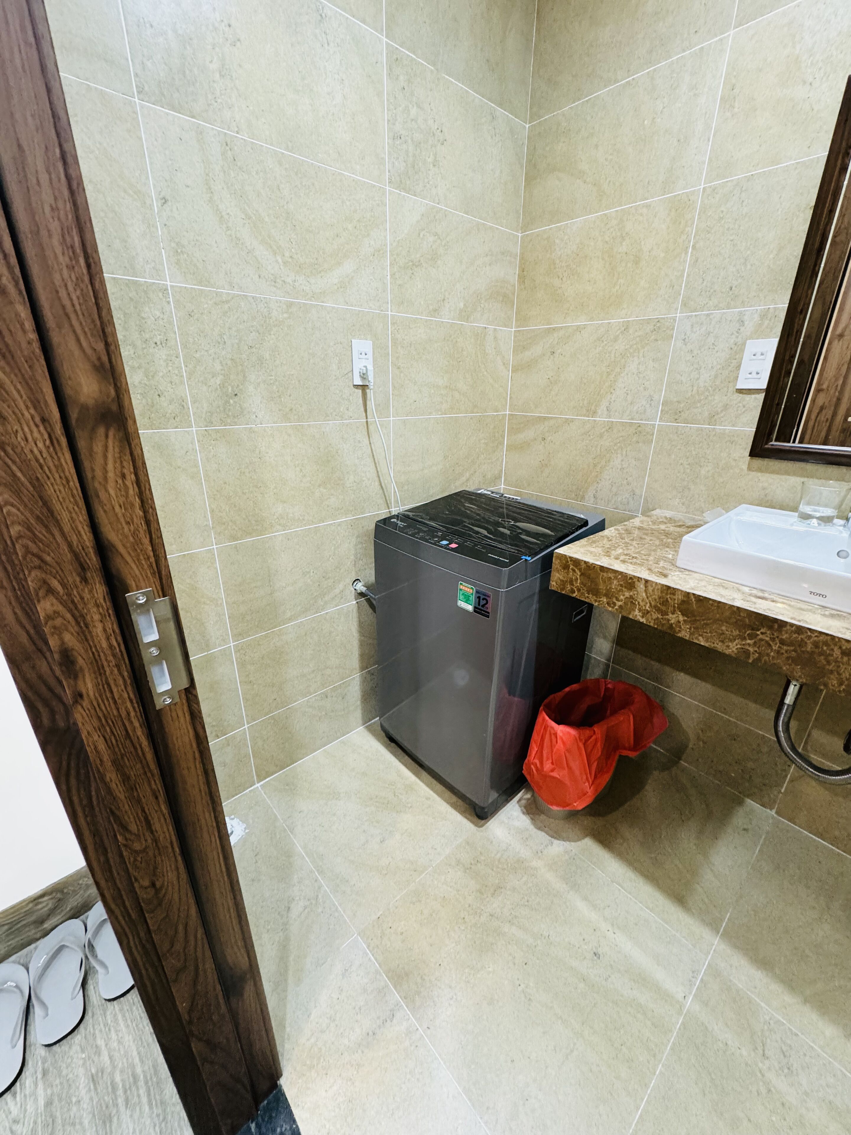 A bathroom with a tiled floor, a sink, a mirror, and a small refrigerator.