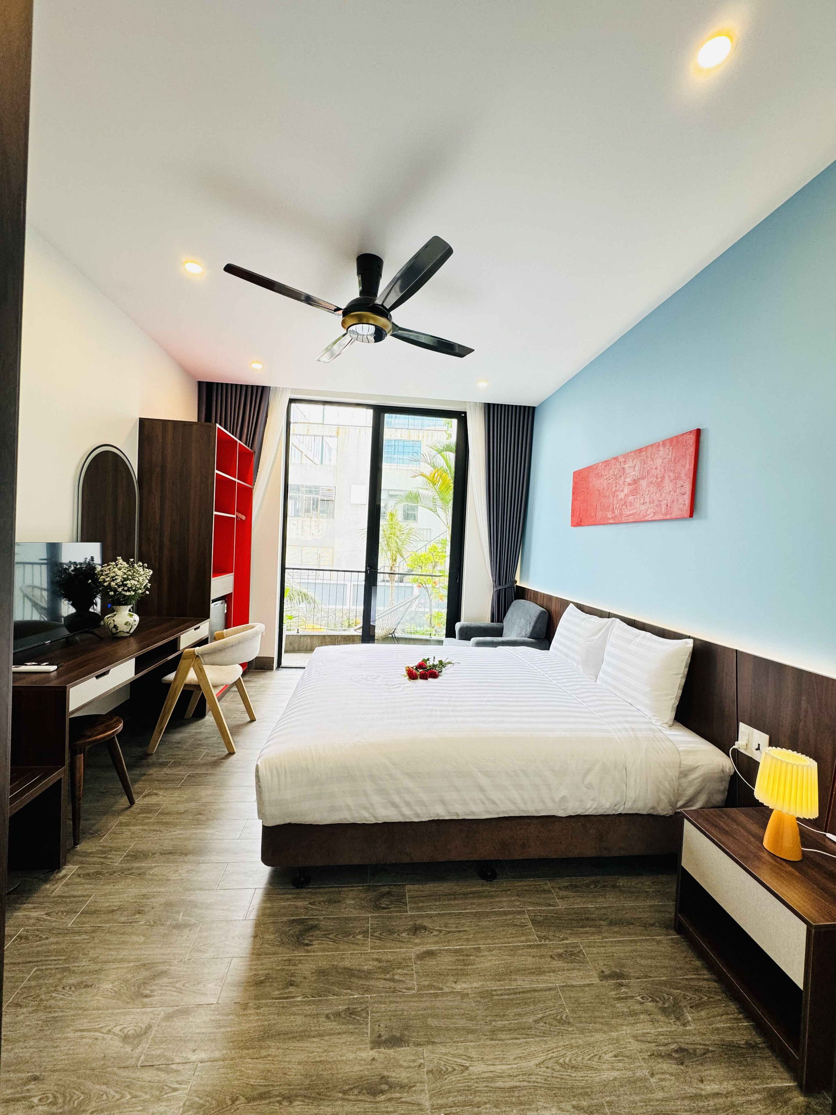 Una habitación de hotel con cama, escritorio, silla y ventilador de techo.