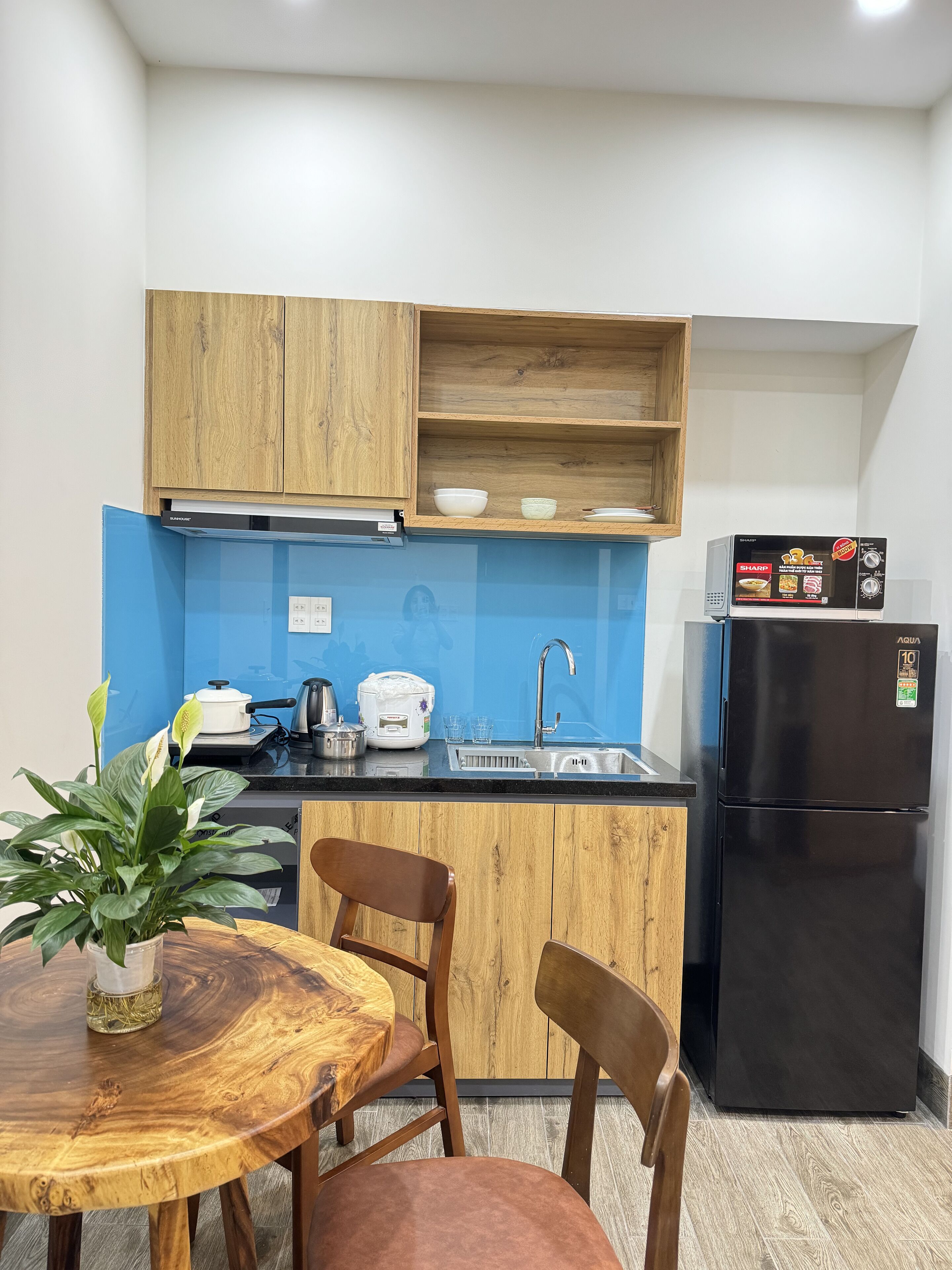 Una cocina compacta con armarios de madera, un refrigerador negro, un lavamanos y un comedor con mesa y sillas.
