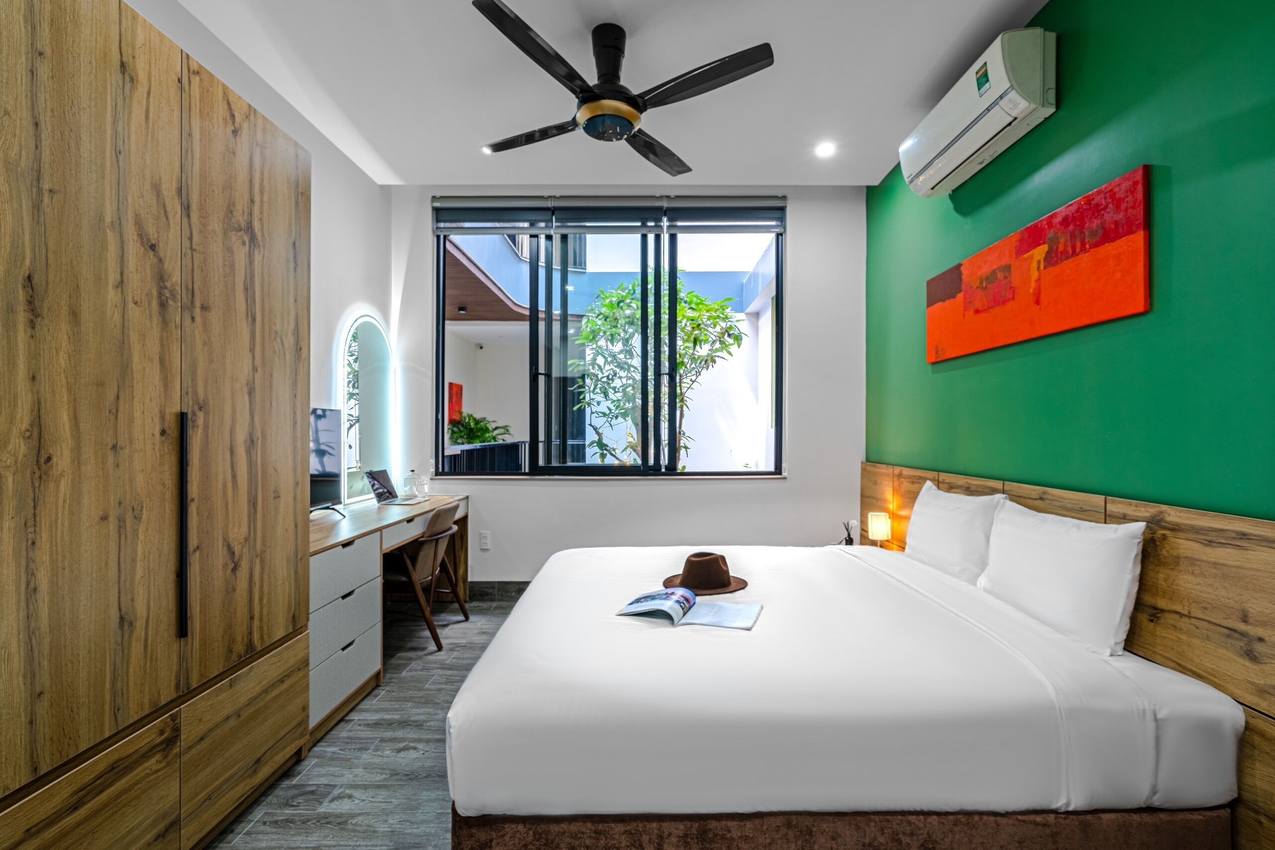 A modern hotel room with a large bed, a desk, and a wardrobe.