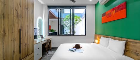 A modern hotel room with a large bed, a desk, and a wardrobe.