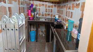 A compact kitchen with a sink, a blue basket, and various kitchen utensils.