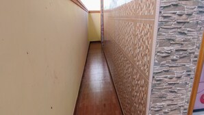 A narrow hallway with tiled flooring and walls featuring a geometric pattern on one side and a stone-like texture on the other.