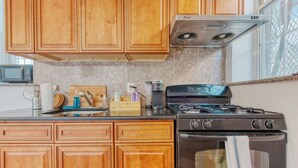 Una cocina con armarios de madera, estufa a gas, microondas y ventana con vistas.