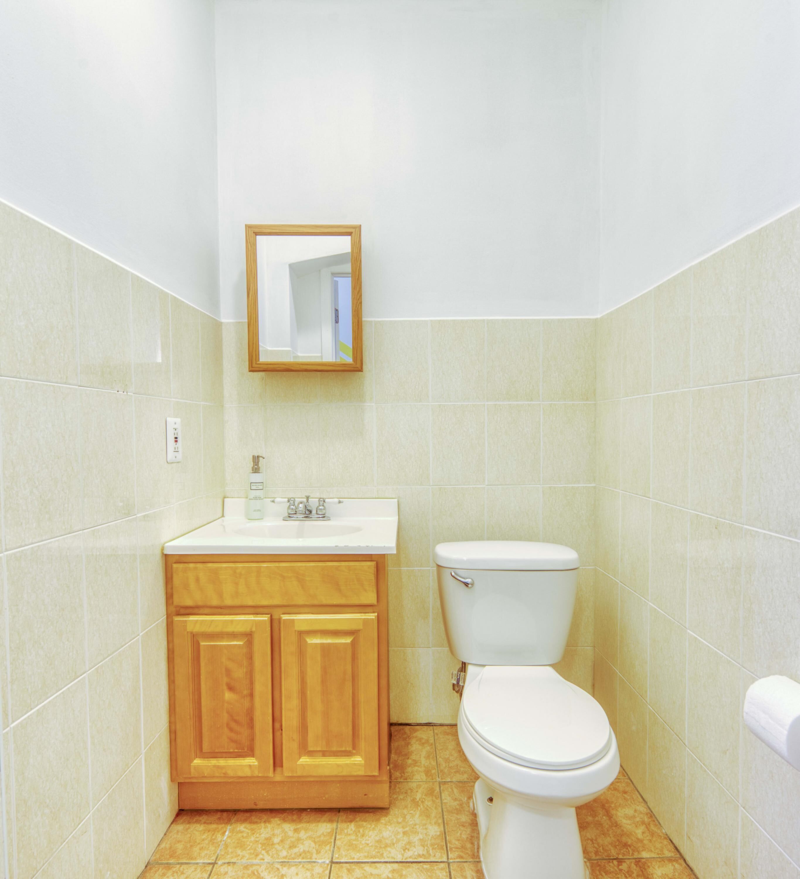 A bathroom with a toilet, sink, and wooden cabinets.