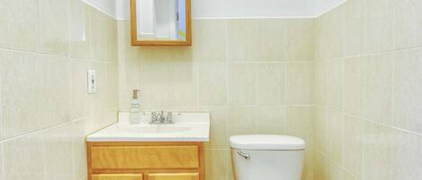 A bathroom with a toilet, sink, and wooden cabinets.