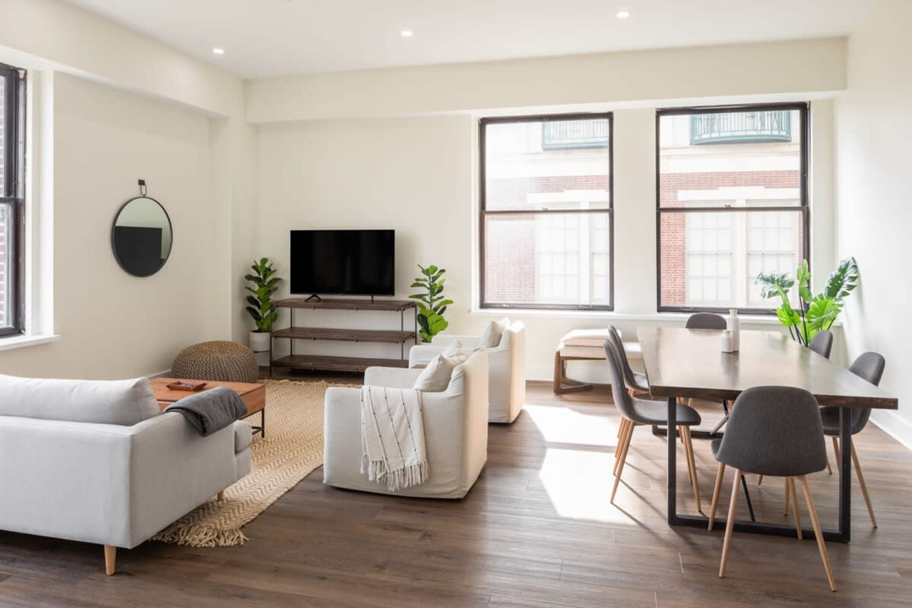 Una sala de estar moderna con un sofá, una mesa de centro, un televisor y un comedor con sillas y una mesa.