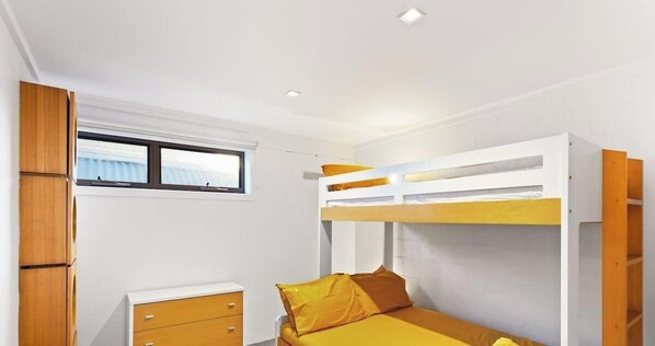 A bunk bed with a window, a wooden cabinet, and a small desk. - Ultimate Beachfront Retreat (Sunderland Bay)