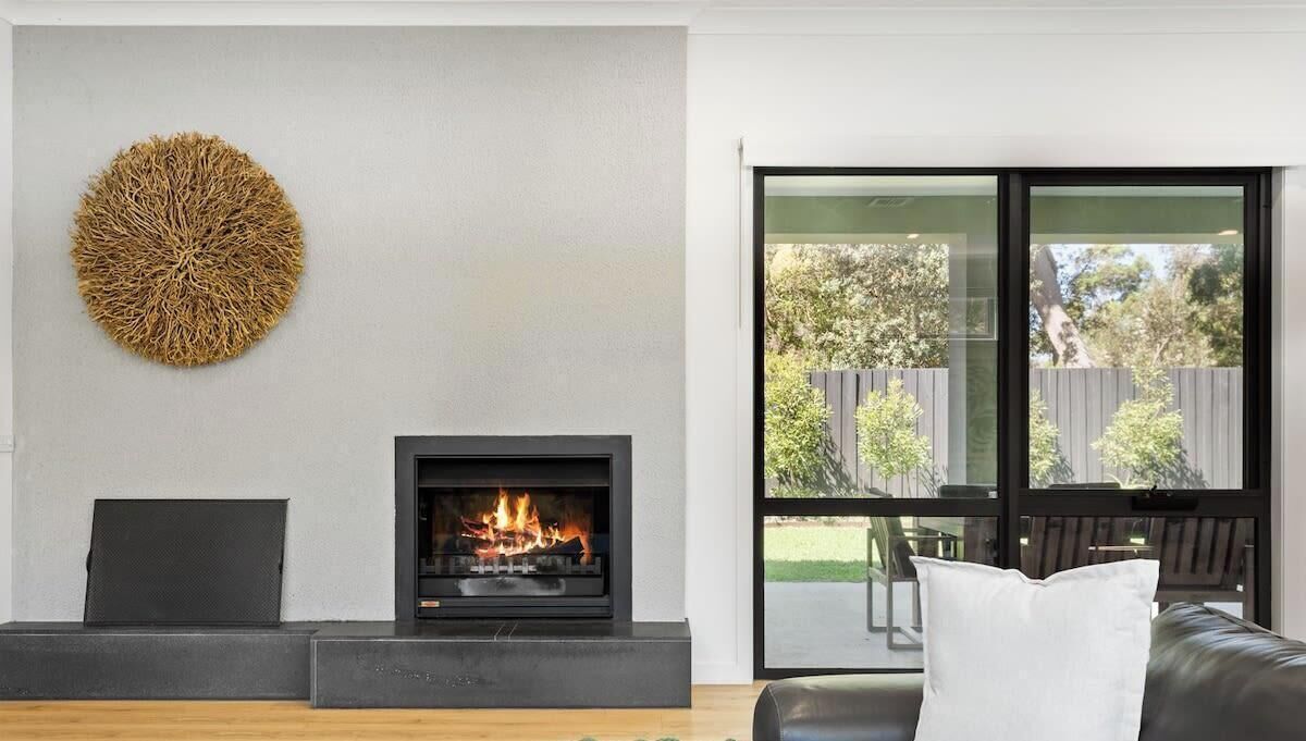 Una sala moderna con chimenea, un ventanal grande y vistas al exterior.