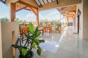 A covered outdoor area with tiled flooring, wooden chairs, and potted plants. - Hotel O Buduran Homestay Syariah (Sidoarjo)