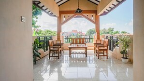A covered patio with a tiled floor, wooden furniture, and potted plants. - Hotel O Buduran Homestay Syariah (Sidoarjo)