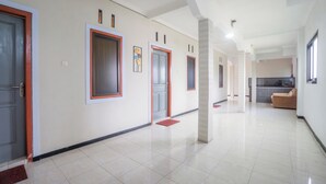 A spacious hallway with multiple doors, a red doormat, and a kitchen area in the background. - Hotel O Buduran Homestay Syariah (Sidoarjo)