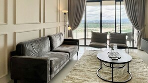 A modern living room with a leather sofa, two armchairs, a round coffee table, and a ceiling fan. - Country Garden Danga Bay (Johor Bahru)